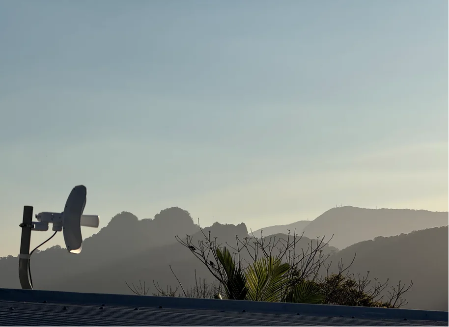 Fixed-wireless antenna mounted on a roof facing tree-covered hills